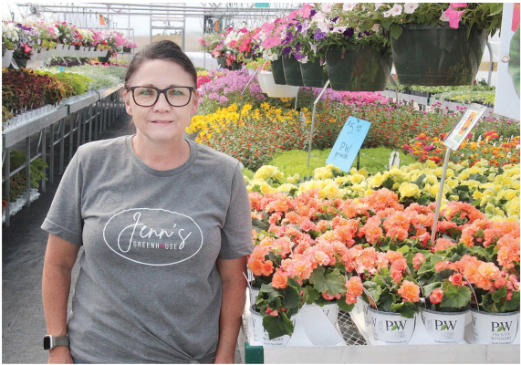 GREENHOUSE OPEN -- Jennifer Beierman with some of the flowers displayed in her new greenhouse northeast of Albion.