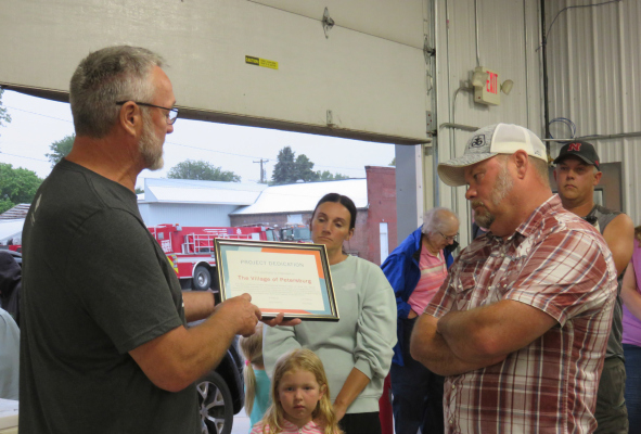 Ross Knott presenting plaque to Village Board Chairman Corey Stokes