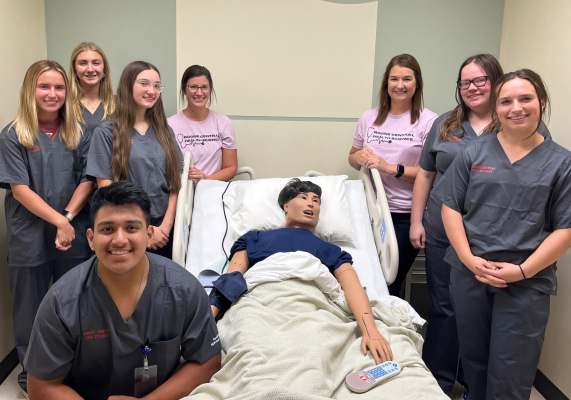 L to R: Miranda McGill, Madison Gompert, Natalie Nelson, Edwin Naranjo Aranda, Mrs. Chelsea Gaunt, Jen Molt-RN, Erica Hall and Madison Reilly pose with manikin by Albion Education Foundation.