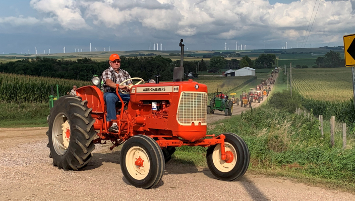 Delmer Pelster Sr. on his Allis-Chalmers entry in the “Tractorcade” at this year’s Nebraska State Antique Tractor and Horse Plowing Bee, turning at “Charlie’s Park” near the entrance tothe show area. Photo by Larry Petsche.