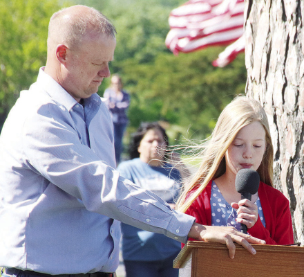 Kalli Carlson is assisted by Legion Commander Chad Carlson as she gives her speech on a windy Memorial Day morning.