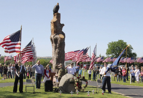 ST. EDWARD Memorial Day participants salute during the Star Spangled Banner at Evergreen Cemetery on Monday. The new feature is the carved eagle near the Memorial Stone.