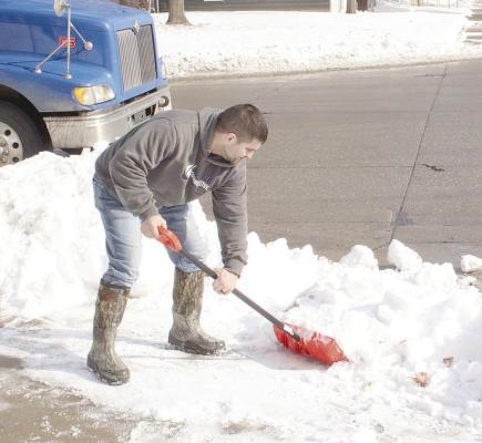 CLEANING UP FROM STORMS -- Temperatures were finally above the freezing mark on Monday, Jan. 22, and area residents were clearing sidewalks and driveways. Above, Weston Ray was removing snow from his sidewalk at Sixth and State in Albion.